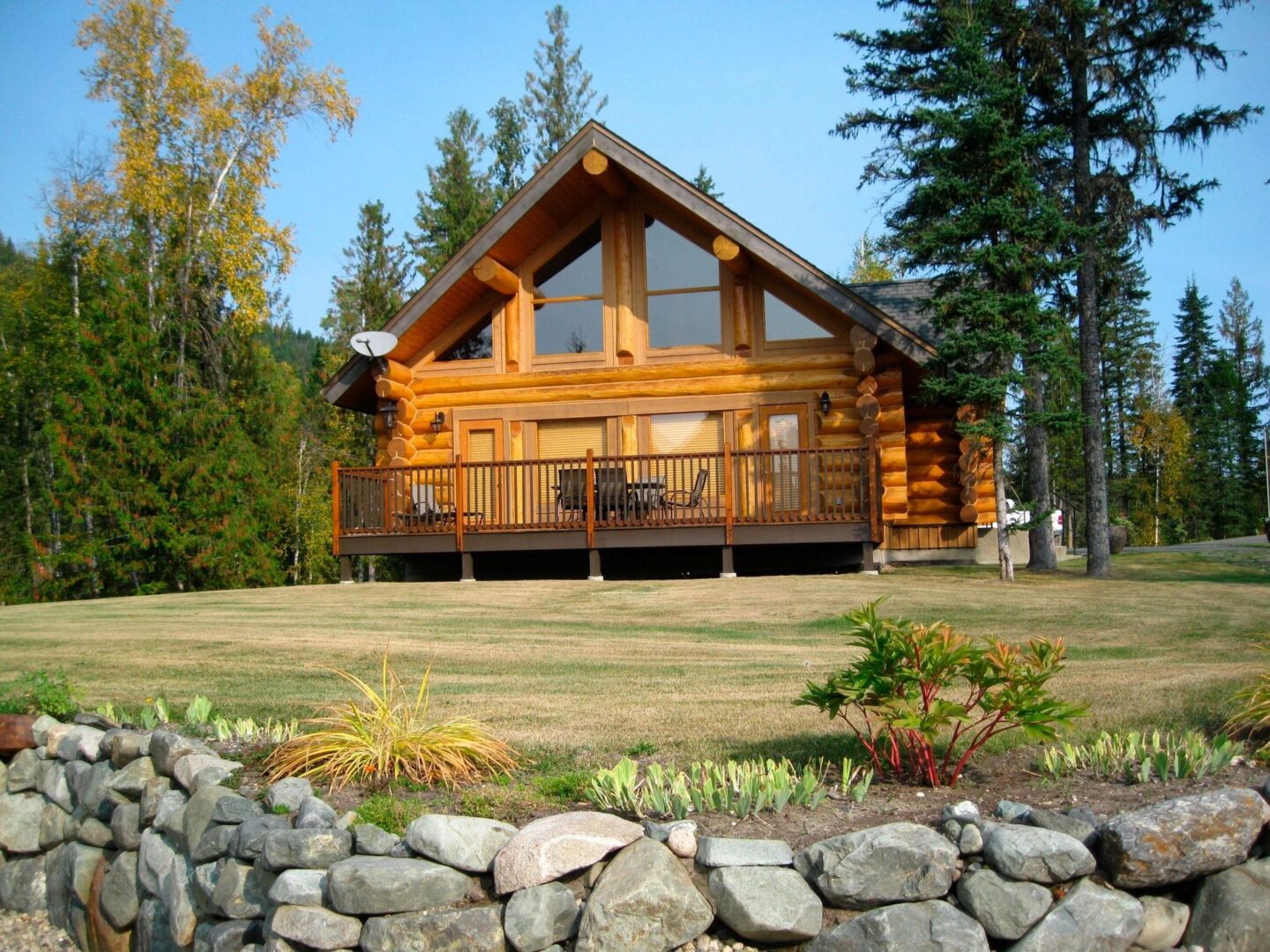 A log cabin with a stone wall in the foreground.